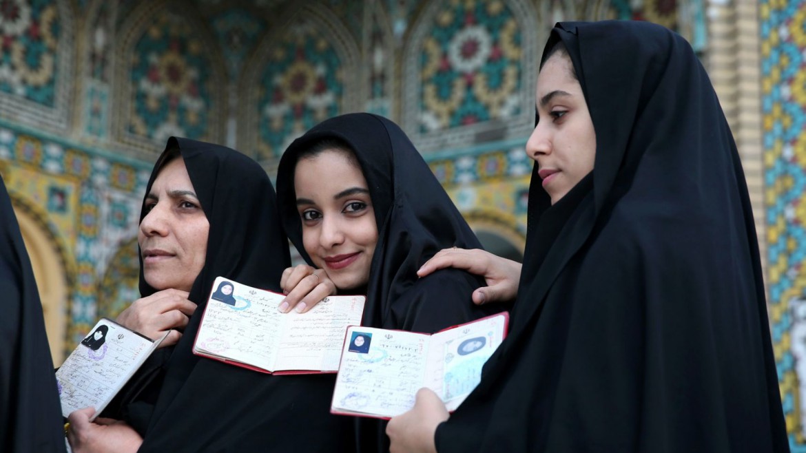 Iranian women show their identification, as they queue in a polling station to vote for the parliamentary and Experts Assembly elections in Qom.AP MPC Journal