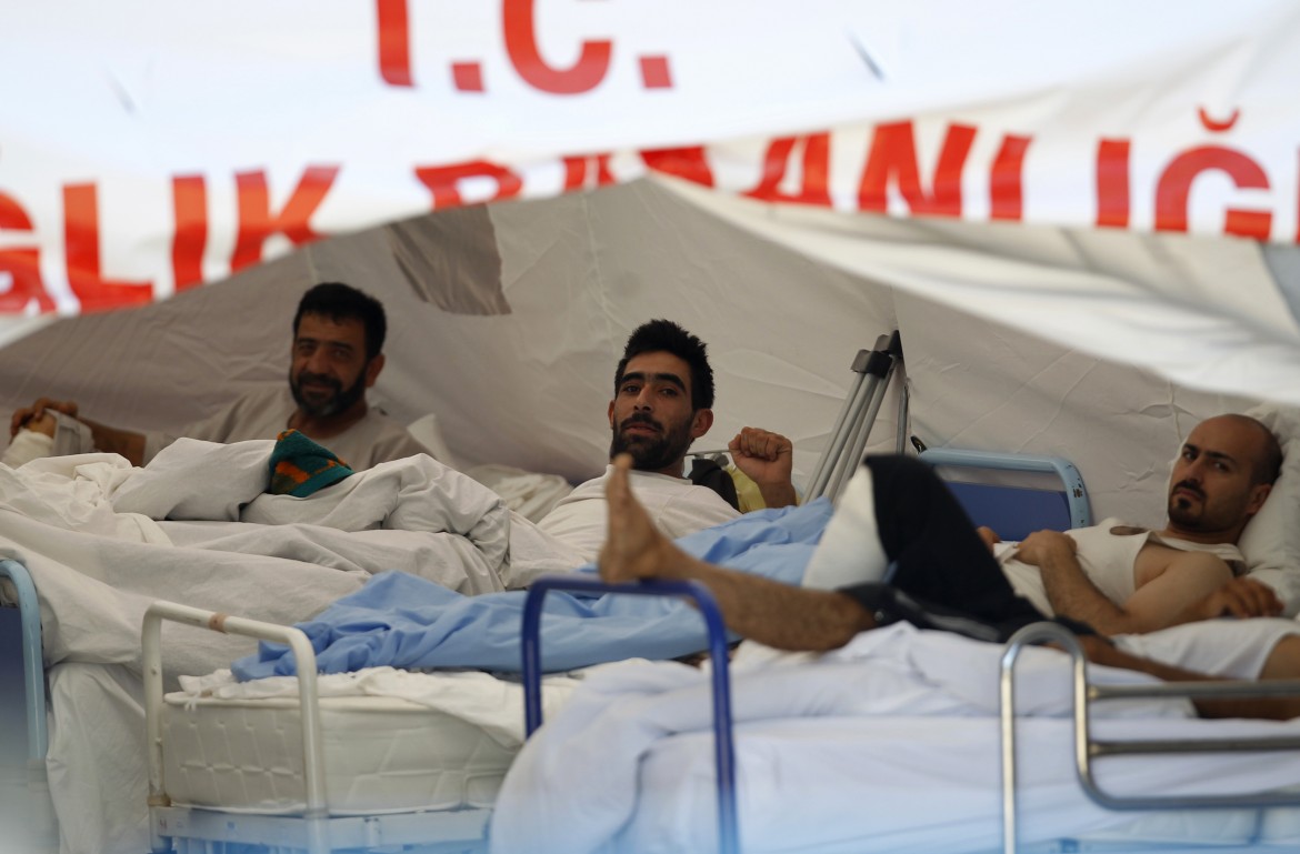 Wounded Syrian men rest in a medical tent next to a refugee camp in the Turkish border town of Yayladagi in Hatay province