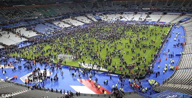 Supporters gather on the pitch at the end of the game ahead of being evacuated from the Stade de France – © Image: AP