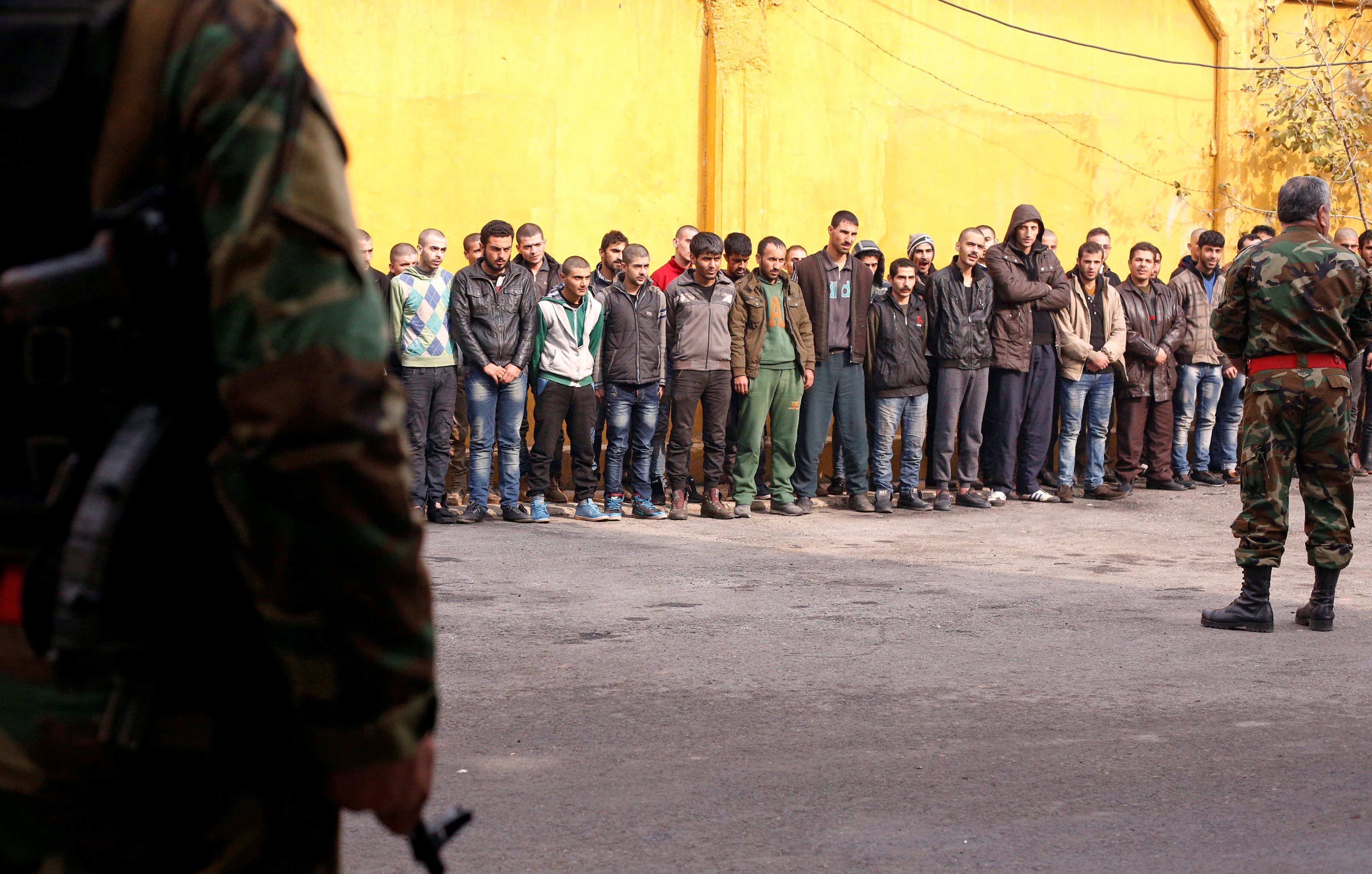 Members of Syria's government military police stand guard as men who were evacuated from the eastern districts of Aleppo are prepared to begin military service. (Reuters/Omar Sanadiki)